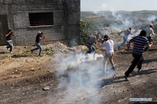 Palestinian protesters run to take cover of gas fired by Israeli soldiers during a protest against the expanding of Jewish settlements in Kufr Qadoom village near the West Bank city of Nablus on April 26, 2013. (Xinhua/Ayman Nobani) 