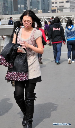 A girl has her coat taken off as she walks on a street in Beijing, capital of China, March 8, 2013. The highest temperature of Beijing hit this year's new high to 19 degrees Celsius on March 8. (Xinhua/Chen Yehua)