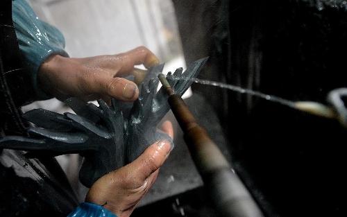  A craftsman polishes a semi-finished handicraft made of chrysanthemum stone in a workshop in Enshi, central China's Hubei Province, Jan. 12, 2013. 