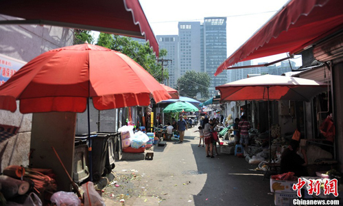 Vendors selling food, vegetables and other necessities line the narrow alleys of Huashiying. As summer temperatures rise, open dumpsters and piles of garbage add to the squalor-like conditions. Photo: Jin Shuo/chinanews.com 