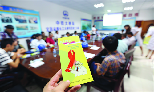 Workers from the Yichang Center for Disease Control and Prevention in Hubei Province pass on knowledge about AIDS prevention and control to migrant workers on August 31. Photo: CFP