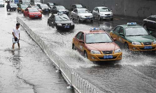 A pedestrian walks in heavy rain in Beijing, capital of China, July 21, 2012. Photo: Xinhua
