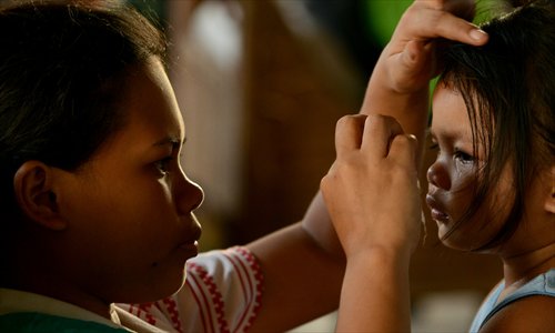 A mother wipes the face of her daughter as they wait to take a flight on a military plane out of Tacloban, Leyte province, central Philippines on Wednesday. International assistance in the wake of the disaster is gaining momentum with many countries and organizations offering pledges of help. Photo: AFP