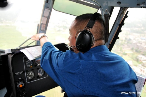A member of the People's Liberation Army Air Force (PLAAF) sits in a military helicopter heading toward Lushan County in quake-hit Ya'an, southwest China's Sichuan Province, April 20, 2013. As of 4:00 p.m. Beijing time (GMT 0800), the PLAAF deployed 10 sorties of transport planes and helicopters for various rescue and relief work, including aerial photography, transporting and disaster situation reconnaissance.(Xinhua/Huang Shubo)