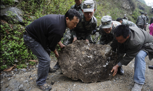 Soldiers from the People's Liberation Army (PLA) Chengdu Military Area Command (MAC) and another two rescuers try to move a huge rock blocking the way to Goushan village, Baoxing county, after a landslide on April 23. Photo: Li Hao/GT