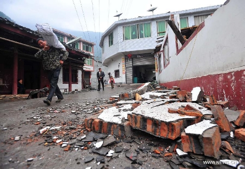 Villagers walk past a damaged house in quake-hit Yuxi Village of Lushan County, southwest China's Sichuan Province, April 23, 2013. A 7.0-magnitude jolted Lushan County on April 20. (Xinhua/Xiao Yijiu) 