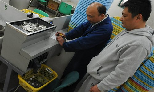 Employees of No.1 Bus Company watch a coin counting machine Thursday. The company has become the first bus company to use the machines to stop counting coins by hand.
Photo: IC