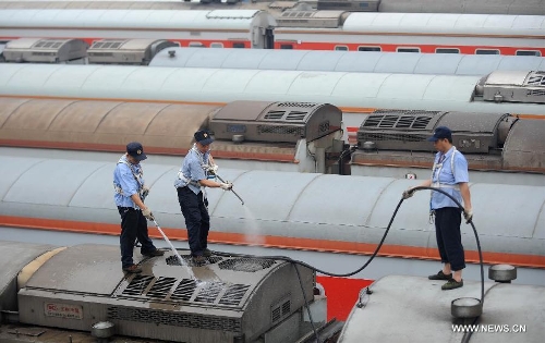 Staff members from the maintenace crew clean a train in Chengdu, capital of southwest China's Sichuan Province, July 8, 2013. Known as the