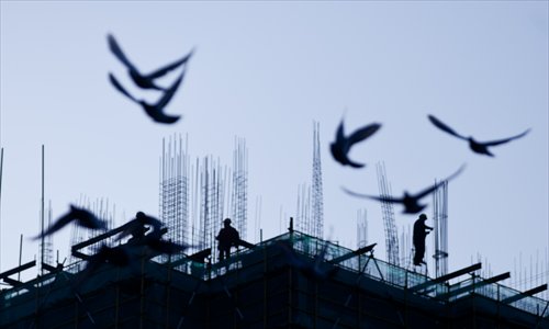 A flight of common city pigeons whirls above a construction site. Photo: Cai Xianmin/GT