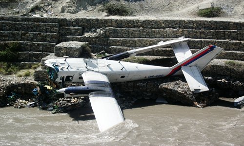 The wreckage of a Nepal Airlines Twin Otter aircraft lies near a river after crashing in Jomsom, some 300 kilometers west of Kathmandu, on Thursday. Twenty-one people were hurt, including eight Japanese tourists, when the small plane skidded off a Nepal airport runway and plunged into the river, police said. Photo: AFP