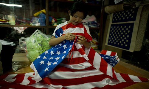 A woman folds US national flags at a shop in Yangon on Friday. US President Barack Obama hopes to demonstrate rising US clout in Asia on his first foreign trip since his reelection, with a tour including a once unthinkable stop in changing Myanmar. Photo: AFP