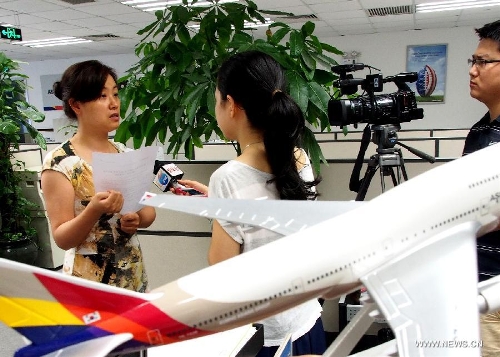 An employee is interviewed by reporters at the office of the Asiana Airlines to Shanghai, east China, July 7, 2013. A total of 141 Chinese citizens were among the 291 passengers aboard the Asiana Airlines flight that crash-landed at the San Francisco International Airport on Saturday, and 90 of the Chinese passengers in total departed from Shanghai via Seoul to the San Francisco airport in the U.S. All the two killed in the crash were identified to be Chinese women, South Korea's transportation ministry said Sunday. (Xinhua/Chen Fei)  