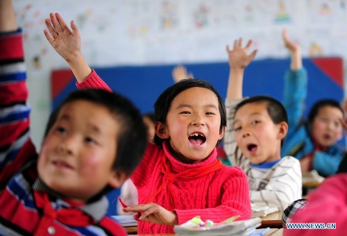 Students of the Hejiabao Central Primary School raise their hands to answer questions during a trial class for the leapfrog education model in Dangchang County, northwest China's Gansu Province, May 27, 2013. The program, aimed at exploring a new education model and starting from 2011, has been carried out in 101 classes of 25 schools, covering about 4,000 students and 102 teachers. (Xinhua/Zhang Meng)