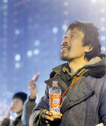 An unnamed homeless man looks up at fireworks in the sky in the central business district in Zhengzhou, Henan Province on Monday. The photo became an instant hit after being uploaded online yesterday, with about 15,000 comments left on Sina Weibo. Photo: CFP