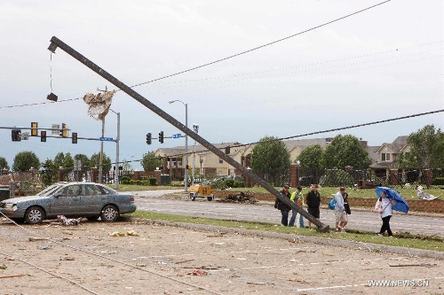Residents walk through a destroyed neighborhood in Moore, Oklahoma, May 21, 2013, one day after a tornado moved through the area. A powerful tornado attacked on Monday afternoon the southern suburbs of the Oklahoma City, capital of the U.S. state of Oklahoma, killing at least 24 people, including 9 children. (Xinhua/Song Qiong)
