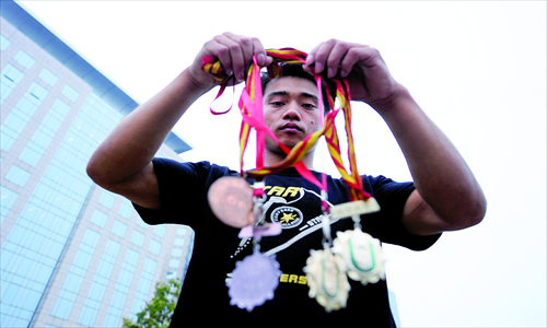 Former gymnast Zhang Shangwu displays his medals during a street perform in Beijing on July 15, 2011. Photos: CFP