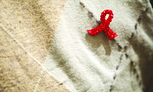 A red ribbon is seen on the chest of a worker for an AIDS control and prevention NGO in Beijing. Photo: CFP