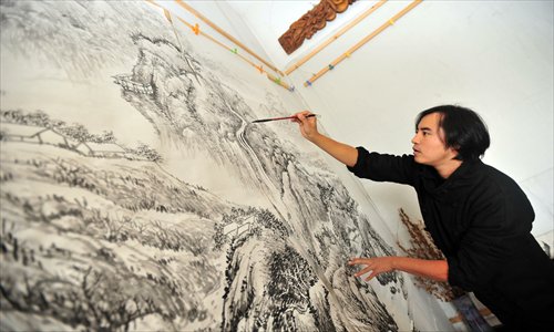 Li Li paints a picture of mountains where he usually goes on patrols. Photo: CFP