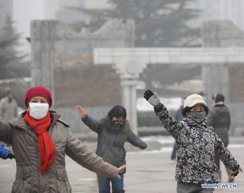 Women wearing masks do morning exercises in fog-enveloped Beijing, capital of China, Jan. 23, 2013. The air quality hit the level of serious pollution in Beijing on Wednesday, as smog blanketed the city. (Xinhua/He Junchang)