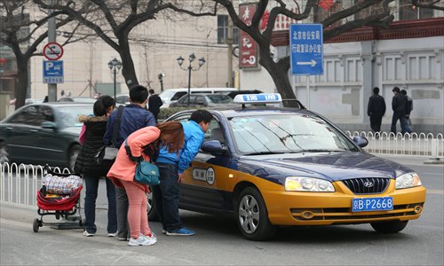 Potential customers talk with a Beijing taxi driver. A new fare increase, which went into effect Monday, may help passengers more easily secure a ride. Photo: CFP