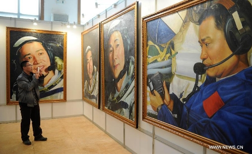 A visitor takes photo of pictures presented during the China's Space Exhibition in Hebei Museum in Shijiazhuang, capital of north China's Hebei Province, April 1, 2013. The exhibition which will last till April 7 included the display of space carriers, rocket-launcher models of the Long March series, paintings and photos related to aerospace. (Xinhua/Wang Xiao)&nbsp; 