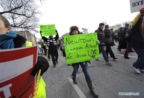 People hold signs against gun violence during a march in Washington D.C., capital of the United States, Jan. 26, 2013. Thousands of people, including family members of victims and survivors of shootings at Virginia Tech University, Sandy Hook elementary school and others, took part in a march for stricter gun control laws here on Saturday. (Xinhua/Zhang Jun) 