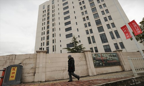 A person walks past a 12-story building alleged in a report on Tuesday by the Internet security firm Mandiant to be the home of a Chinese military-led hacking group in Shanghai's northern suburb of Gaoqiao. 
Photo: AFP