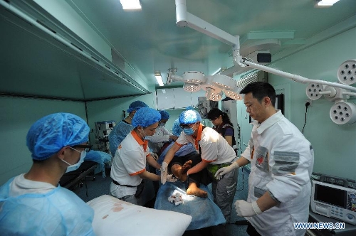 Health workers of Chongqing emergency medical service team give treatment to an injured person transported from the quake-hit Baoxing County in southwest China's Sichuan Province, April 21, 2013. al authorities. (Xinhua/Li Jian) 