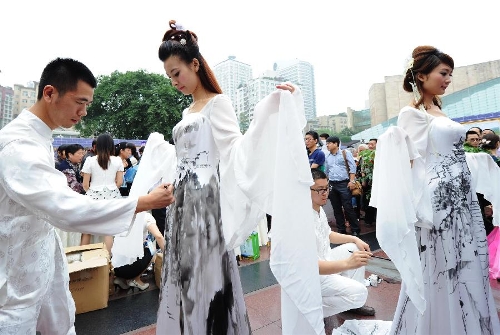 Artists draw on models' costumes during the opening ceremony of the China Tourism Day and the 3rd Western China Tourism Industry Expo, in Chongqing, southwest China, May 19, 2013. Chongqing is the main venue for the 2013 China Tourism Day. (Xinhua/Li Jian)