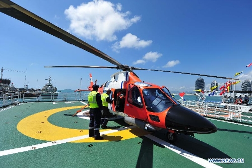 Staff members examine the helicopter carried by marine patrol ship 