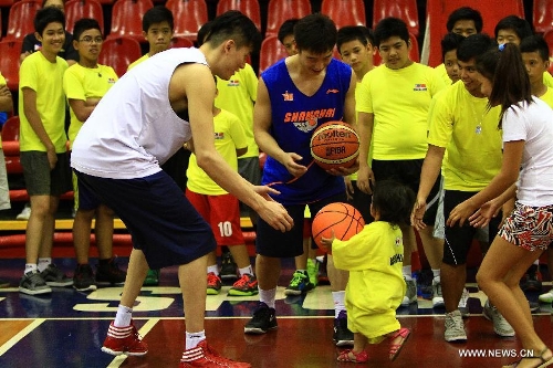 Players from the Shanghai Sharks play basketball with a Filipine girl during a basketball clinic in Pasig City, the Philippines, May 5, 2013. Yao and his Shanghai Sharks are in Manila on a friendly visit. They will attend two exhibition games respectively with the Smart Gilas Team and the Philippine Basketball Association (PBA) Selection. (Xinhua/Rouelle Umali) 
