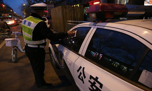 A police officer sticks a parking ticket on a police car in Dongsi Sitiao, Dongcheng district.  The Beijing Traffic Management Bureau has recently strengthened measures to ease traffic congestion in the city. Photo: CFP