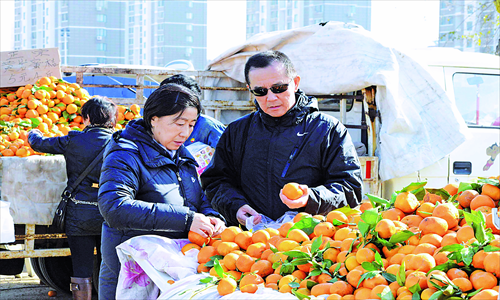 Customers select oranges at a fair in Qingdao, Shandong Province, Thursday. Such fairs, where a variety of food products and other items are sold, have been losing favor with shoppers as supermarkets and retail stores become more common. Photo: CFP