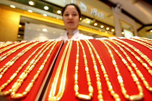 A saleswoman arranges gold jewelry in a store in East China's Jiangsu Province. Photo: CFP