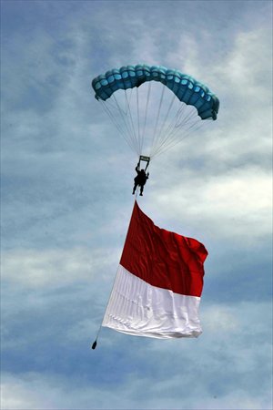 A paratrooper carries a flag during a parade of the 67th anniversary commemoration of the Indonesian Air Force at an airbase in Jakarta on Tuesday.  The Indonesian Air Force has more than 30,000 personnel equipped with more than 100 combat aircraft, including Su-27 and Su-30. Photo: AFP