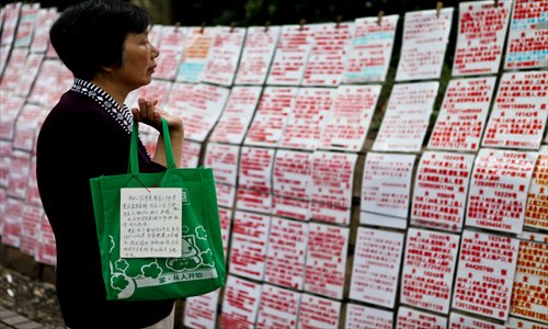 A mother browses the personal information of women seeking husbands posted at People's Park last month. Mothers often go to the downtown park to help find spouses for their unmarried children. Photo: CFP