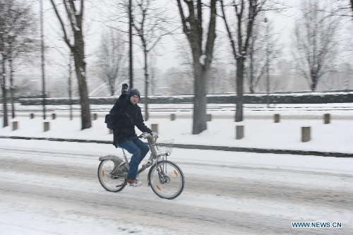 A man rides a bicycle on a snow-covered road in Paris, France, Jan. 20, 2013. French weather agency Meteo France has put 55 departments, including the Ile-de-France (Paris and its suburb), under orange alert and decided to maintain the alert system in these areas till Sunday afternoon based on lasting snowfalls in these areas where the snow is expected to be thick as up to 20 centimeters. (Xinhua/Li Genxing)