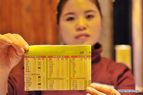  A working staff shows the menu at a hot pot restaurant in Lanzhou, capital of northwest China's Gansu Province, Jan. 30, 2013. A 
