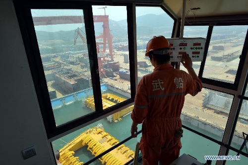 A worker operates a crane to lift the newly-built deep-sea engineering equipment in Qingdao, east China's Shandong Province, July 3, 2013. With four sets of buoys and 16 sets of foundations, the deep-sea engineering equipment, the world's largest of this kind, was built and delivered by Wuchang Shipbuilding Industry Co., Ltd. to Petrobras as part of the Sapinhoa-Lula NE BSR Buoys & Foundations Project, which will be installed in an offshore oilfield in Brazil to work for a period of 27 years. The equipment is able to fit in deeper and more complicated marine environment and has extensively enlarged the scope of offshore oil exploitation, said Victor Bomfim, senior vice president of the project contractor Subsea 7 S.A. (Xinhua/Wan Houde)