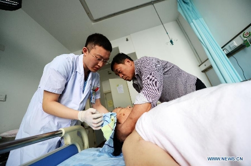 Wu Wei (L), a nurse of the 1st Affiliated Hospital of Harbin Medical University, washes hair for a patient in the hospital in Harbin, capital of northeast China's Heilongjiang Province, May 11, 2013. Male nurses in China are scarce, whose number accounts for merely one percentage of the total nurses in the country. Many people attribute the scarcity to society's view point that nursing is a women's job. Women are seen as more careful and patient than men, but, in general, male nurses are physically stronger or more energetic than women. They are particularly needed in Intensive Care Units, emergency departments, psychiatric hospitals and so on. (Xinhua/Wang Kai)