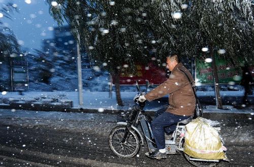 A man rides an electric vehicle on a snow-covered street in Changchun, capital of Northeast China's Jilin Province, October 22, 2012. Most parts of Jilin witnessed snowfall on Monday. Photo: Xinhua