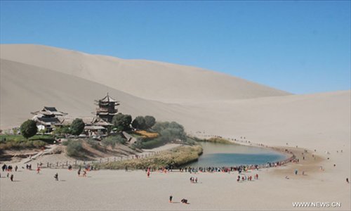 Tourists ride camels at the scenic spot of Crescent Lake in Dunhuang City, northwest China's Gansu Province, October 4, 2012. Dunhuang, a major stop on the ancient Silk road well known for its Mogao Caves (Caves of 1,000 Buddhas), Crescent Lake and Mingsha Mountain, has attracted large numbers of tourists from both home and abroad during the National Day holiday. Photo: Xinhua