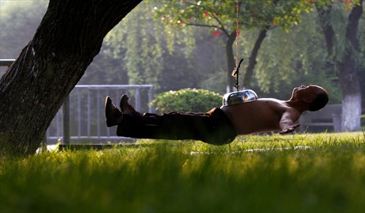 Ah Qi, an ironsmith, hangs in the air with his belly stuck to a bowl suspended from a tree in Tongxiang, Zhejiang Province. The 69-year-old man, a kung fu enthusiast, is locally well-known for this stunt that can last minutes. Photo: CFP