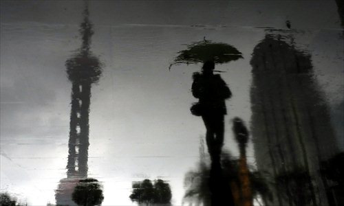 A woman walks in the rain Thursday in Pudong New Area. Although summer began in Shanghai on Saturday, the temperature fell to 20 C Thursday due to the rain. Photo: Yang Hui/GT