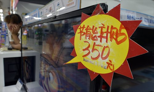A shop assistant relaxes beside a television set for sale in Taiyuan, Shanxi Province, Tuesday. Local electronics retailers in Taiyuan have been trying to encourage shoppers to buy energy-saving appliances before the end of this month, when government subsidies on such goods will expire, yet few local customers have reacted to the promotions. Photo: CFP
