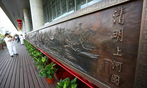 Visitors appreciate a bronze relief of Riverside Scene at Qingming Festival at Pudong Library Monday. The 20.5-meter-long handmade relief was created by folk artist Li Wanshan. Photo: IC