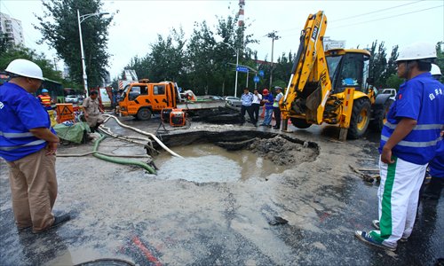 Staff from the Beijing Waterworks Group repair damaged water pipes, which led to a sinkhole forming on August 1 in Wangjing, Chaoyang district. Nearly 100 sinkholes have appeared across the city since the July 21 storm. Photo: Guo Yingguang/GT
