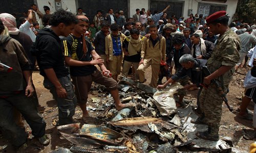 Yemeni security forces and citizens look at some of the debris from a Russian-made Yemeni military jet after it crashed into a residential district of the capital Sana'a on Monday, killing the pilot, officials said. Photo: AFP