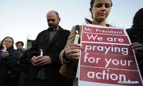 Supporters of gun control legislation hold candles and placards during a rally to pay respect for the shooting victims in front of the White House in Washington, capital of the United States, Dec. 14, 2012, following a deadly shooting spree in an elementary school in Newtown, Connecticut, which took place earlier in the day. Photo: Xinhua