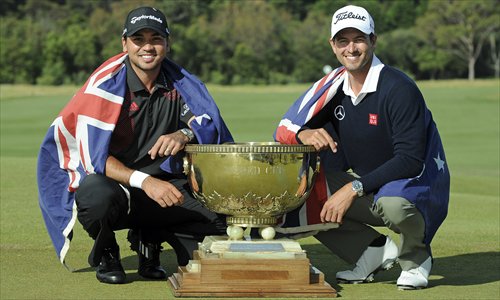 Jason Day (left) of Australia and compatriot Adam Scott pose with the World Cup of Golf trophy after winning the team event in Melbourne on Sunday. Photo: IC